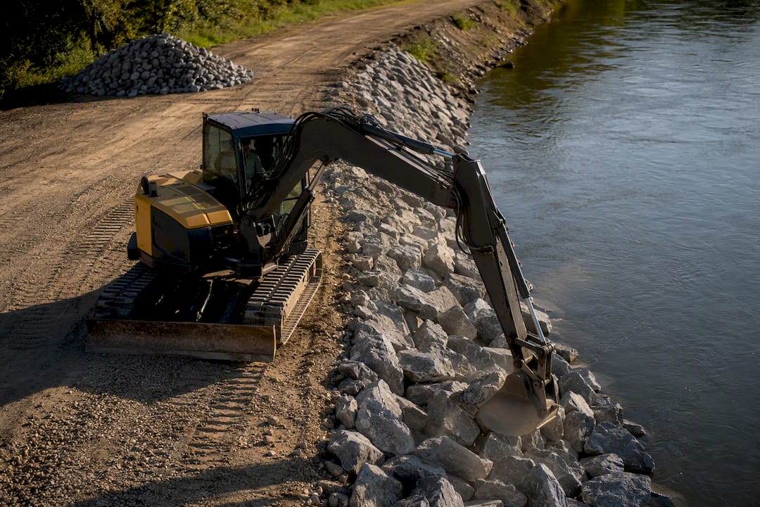 Excavator placing riprap on bank