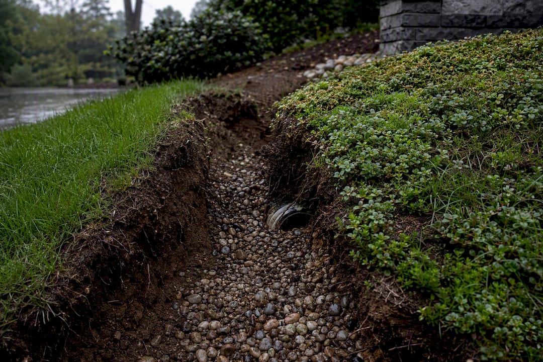 Erosion exposing a French drain gravel bed