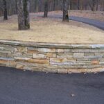 Curved cut-limestone wall, along a drive, with a cut cap