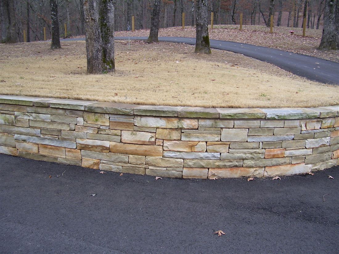 Curved cut-limestone wall, along a drive, with a cut cap