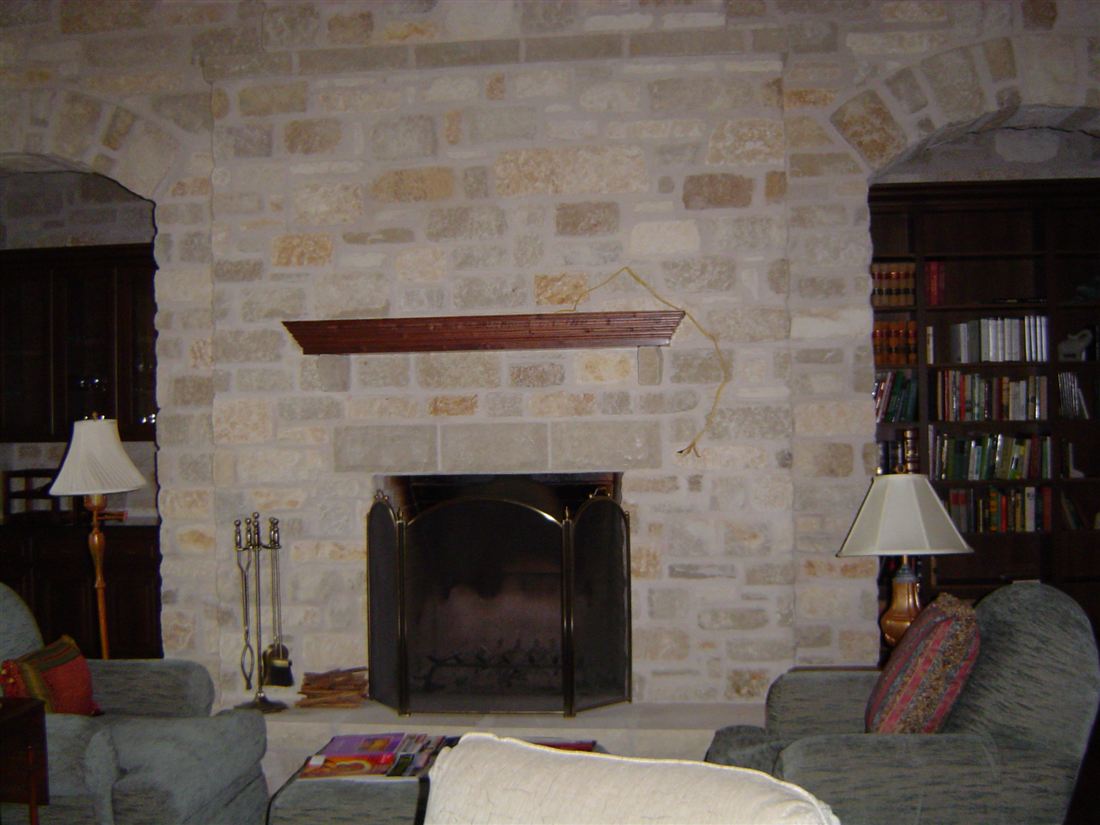 Fireplace wall, cut limestone between the bookcases, timber mantel