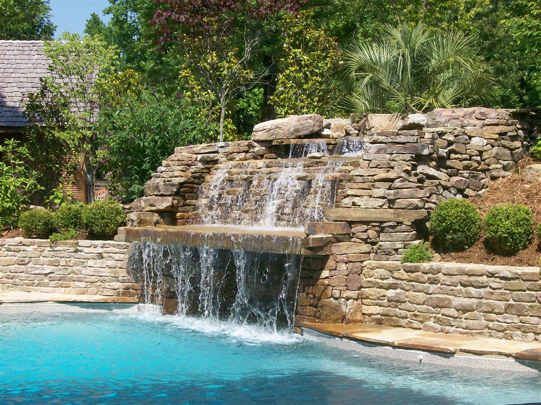 Grotto waterfall, boulders and ledge stone spilling into the pool