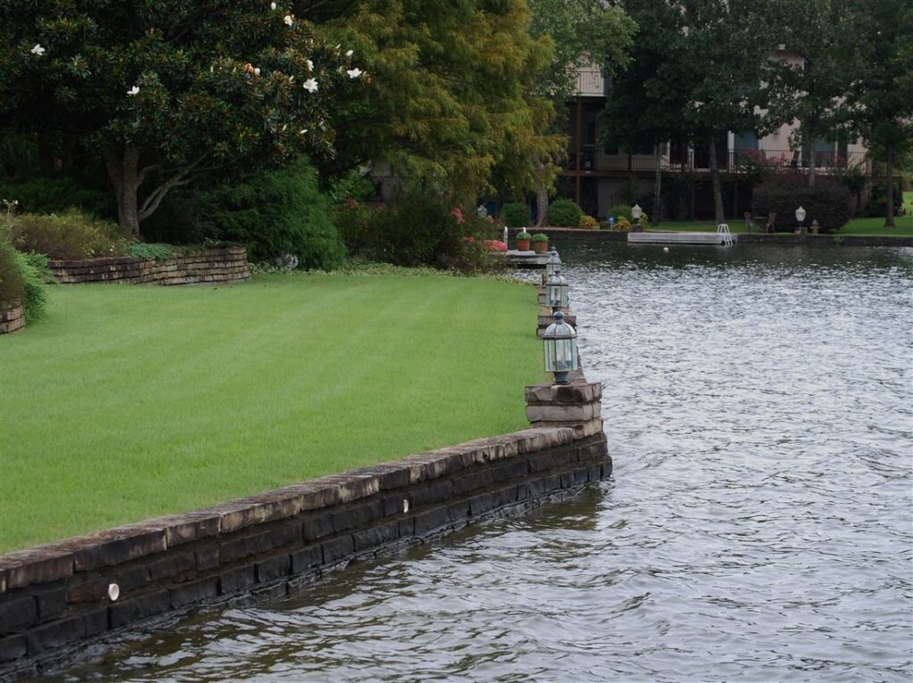 Seat wall over a stone seawall, lawn to the water, lantern pillar