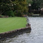 Seat wall over a stone seawall, lawn to the water, lantern pillar