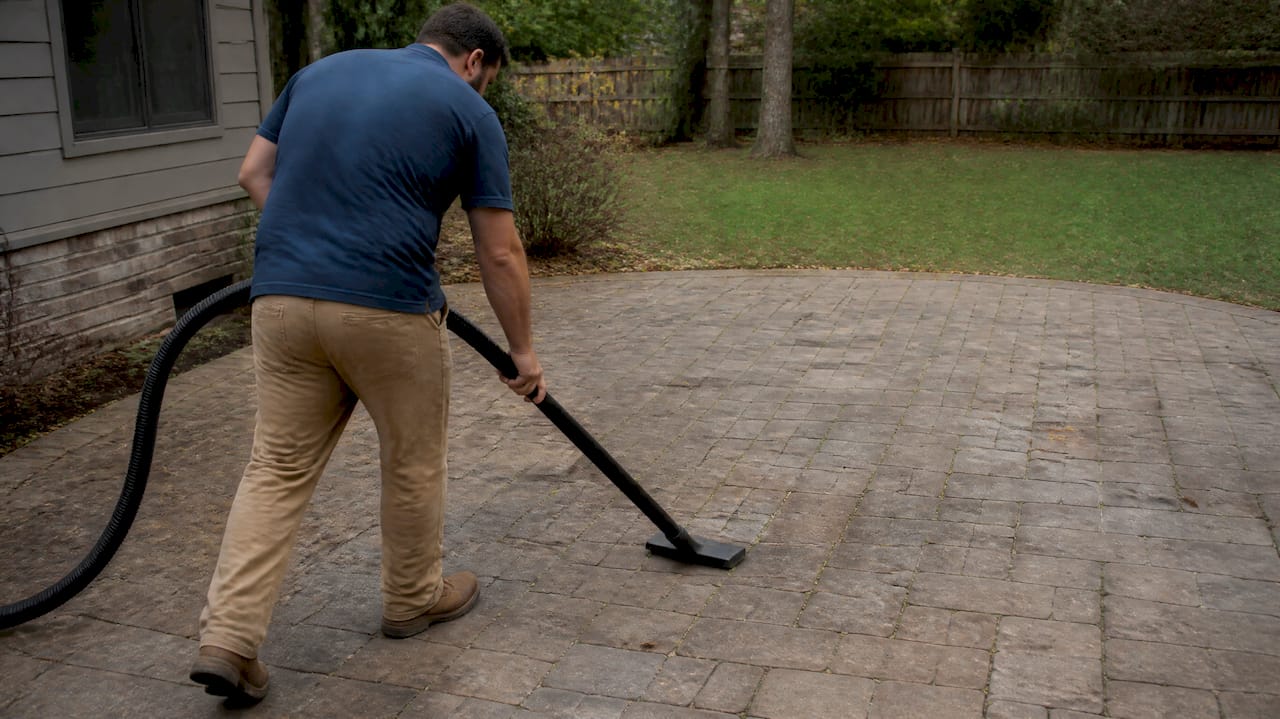 Homeowner vacuum sweeping patio joints